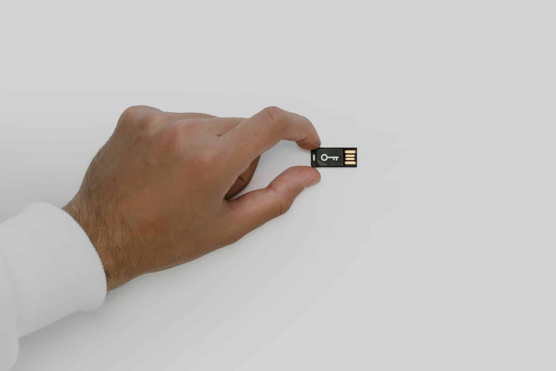 Hand Holding a USB Flash Drive with Key Symbol
