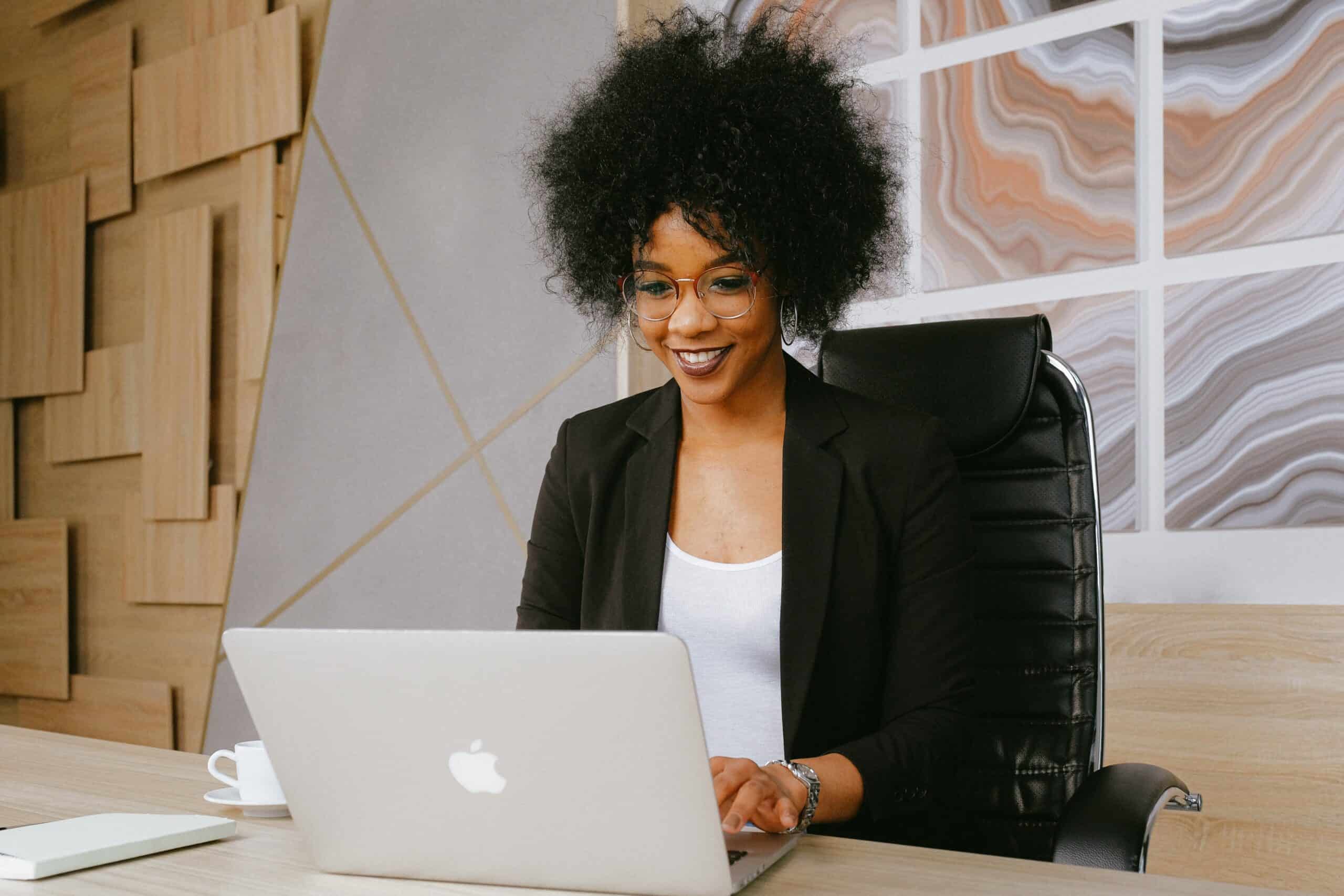 Woman In Black Blazer Sitting On Black Office Chair working on laptop computer